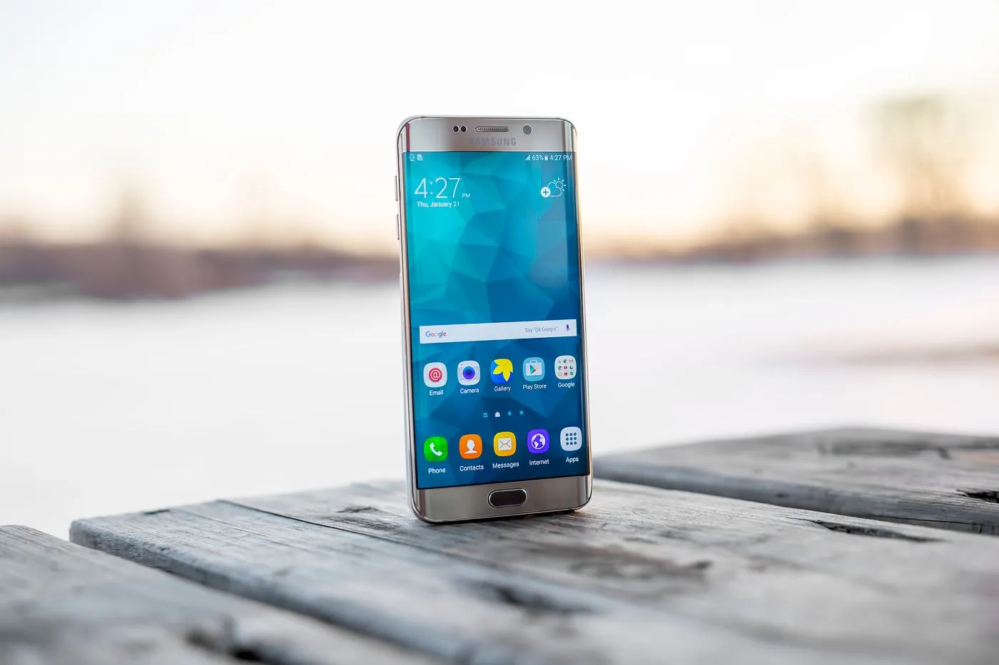 A smartphone standing on a wooden surface in warm evening light